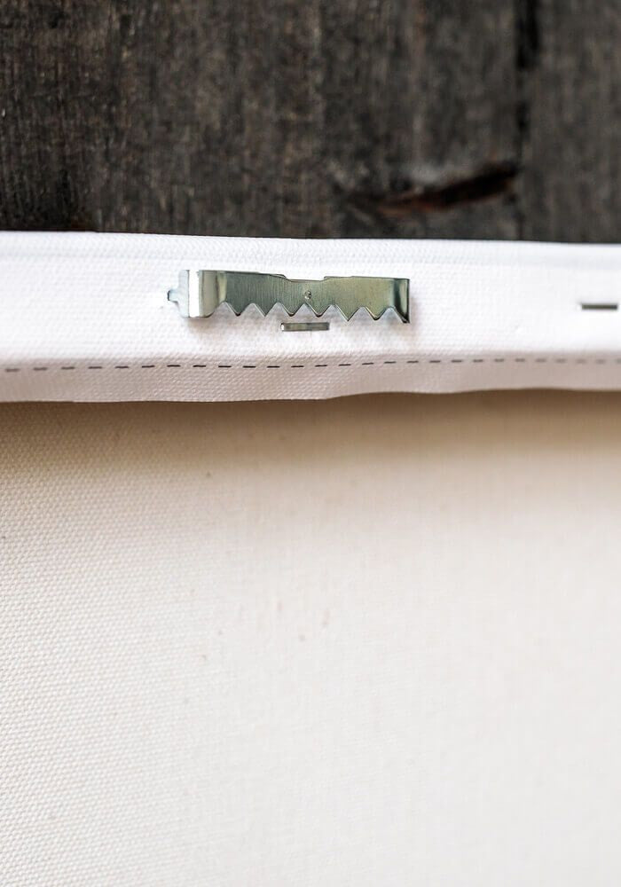 Close up of back of white canvas showing silver wall mount