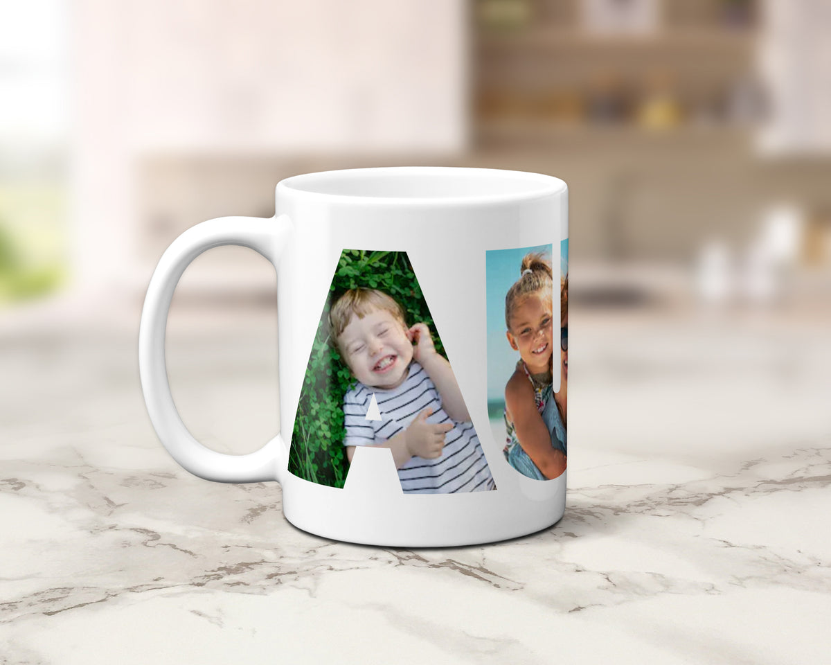 A white ceramic coffee mug with custom printed photos arranged in a large letter 'A' design, sitting on a light marble countertop with a blurred kitchen background.