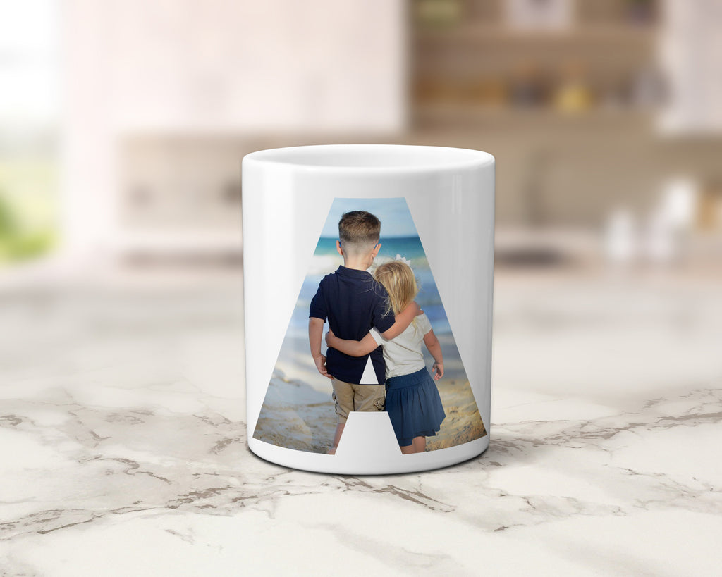 A white ceramic mug with a custom printed photo of two children from behind, set against a blurred kitchen background on a marble countertop.