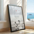 Framed custom engagement map print featuring a black and white map, red heart, ‘ENGAGED’ text, couple’s names and engagement date, with a couple portrait at the bottom