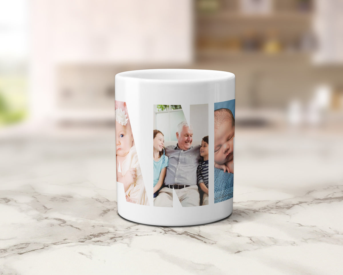 A white ceramic coffee mug with custom family photos within the letters spelling GRANDPA wrapped around its side, set on a light marble countertop with a blurred kitchen background.