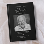 A black personalised keepsake book titled 'Letters to My Dad in Heaven' with a black and white portrait photo of an elderly man on the cover, photographed on soft white fabric.
