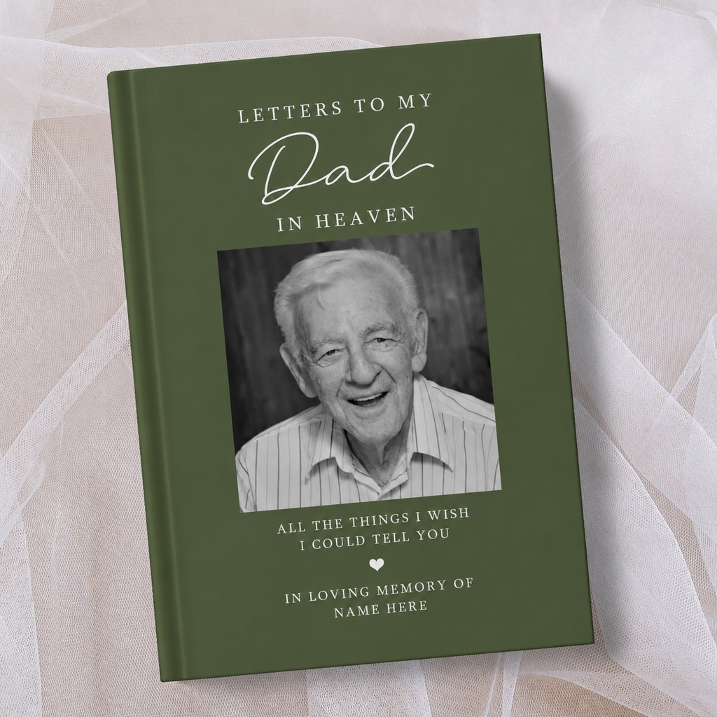 A personalised hardcover keepsake book titled 'Letters to My Dad in Heaven' in olive green, featuring a black and white portrait photo of an elderly man on the cover, displayed on a soft beige fabric background.