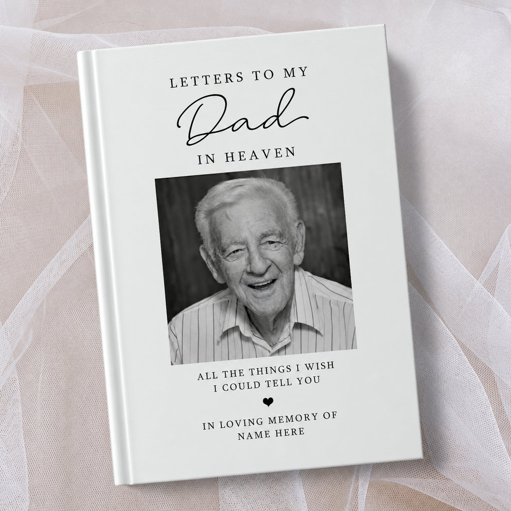 A hardcover book titled 'Letters to My Dad in Heaven' with a black and white portrait photo of an elderly man on the cover, styled on a white background with sheer white tulle.