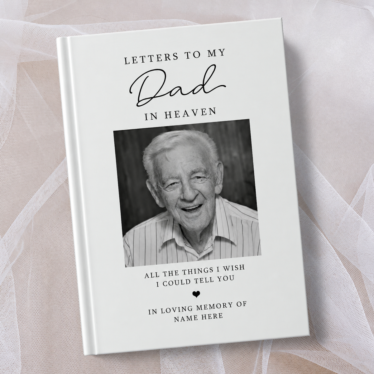 A hardcover book titled 'Letters to My Dad in Heaven' with a black and white portrait photo of an elderly man on the cover, styled on a white background with sheer white tulle.