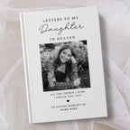 A personalised hardcover book titled 'Letters to My Daughter in Heaven' with a black and white photo of a woman on the cover, styled on a soft beige fabric background.