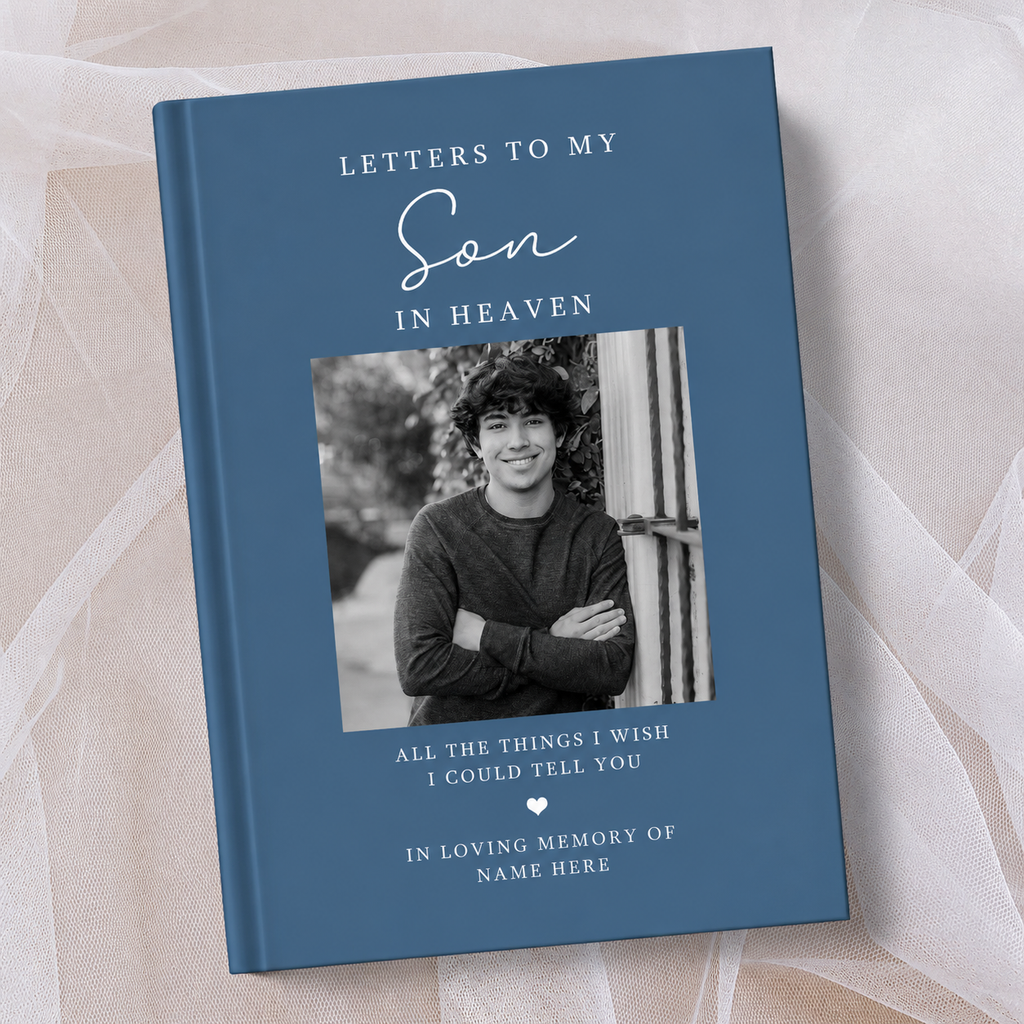A hardcover book titled 'Letters to My Son in Heaven' with a slate blue cover, featuring a black and white photo of a young man on the front. The book is displayed on a soft beige fabric background.