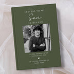 A personalised hardcover book titled 'Letters to My Son in Heaven' in olive green, featuring a black and white photo of a young man on the cover, displayed on a soft beige fabric background.