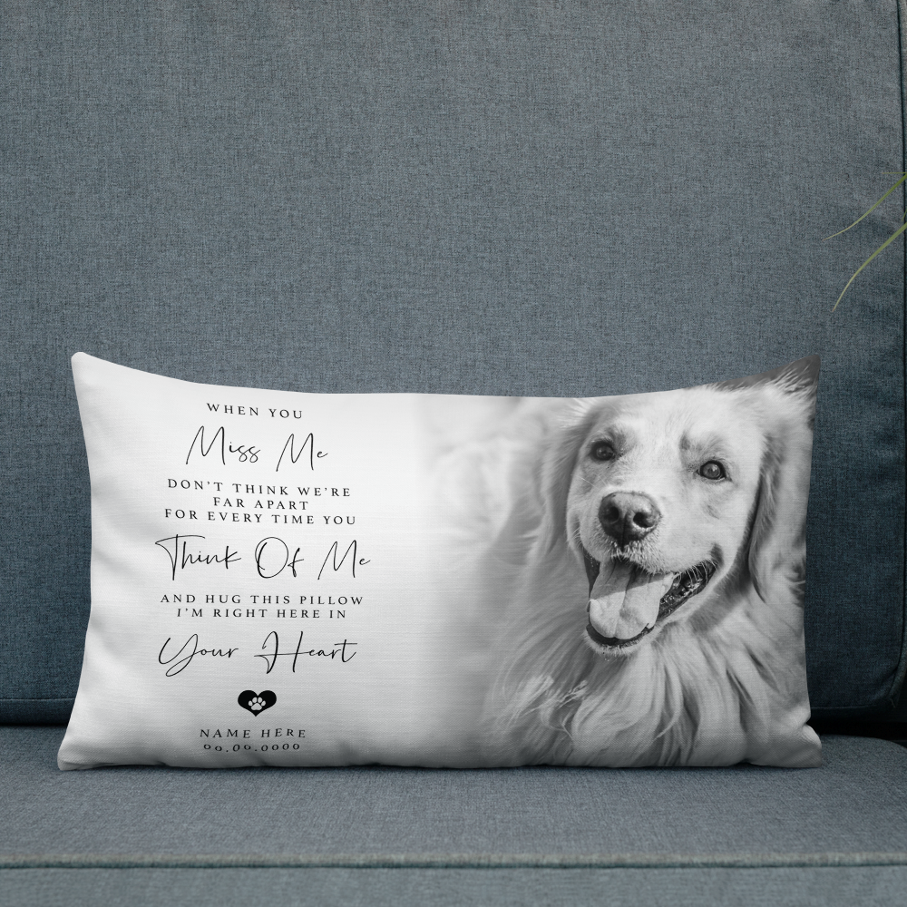 A rectangular pet memorial throw pillow featuring a black and white photo of a golden retriever and sentimental text, displayed on a blue fabric sofa.