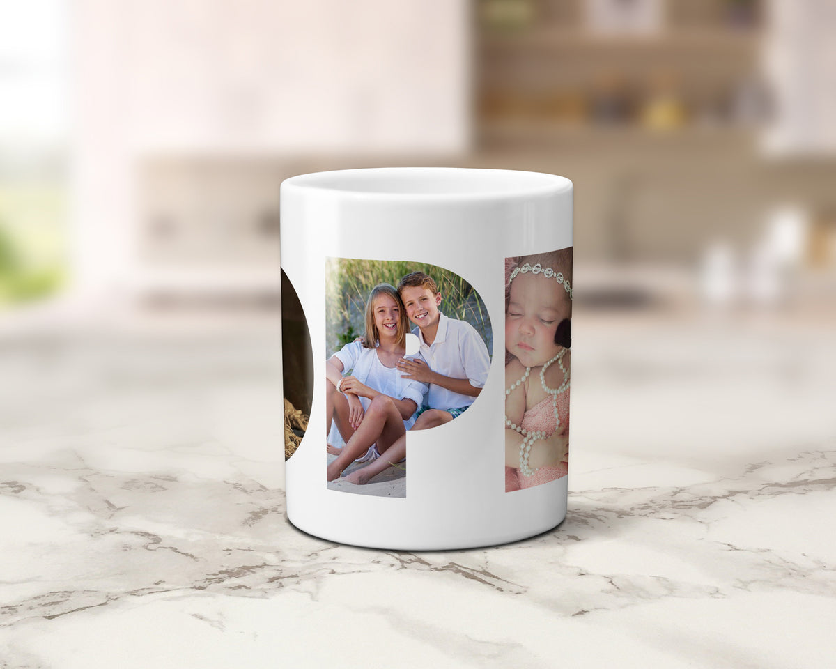 A white ceramic mug with custom photo prints, displayed on a light marble countertop with a blurred kitchen background.