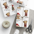 Three wrapped Christmas gift boxes with teddy bear illustrations and 'Merry Christmas Noah' text, tied with twine and styled with scissors, string, and paper tags on a grey surface.