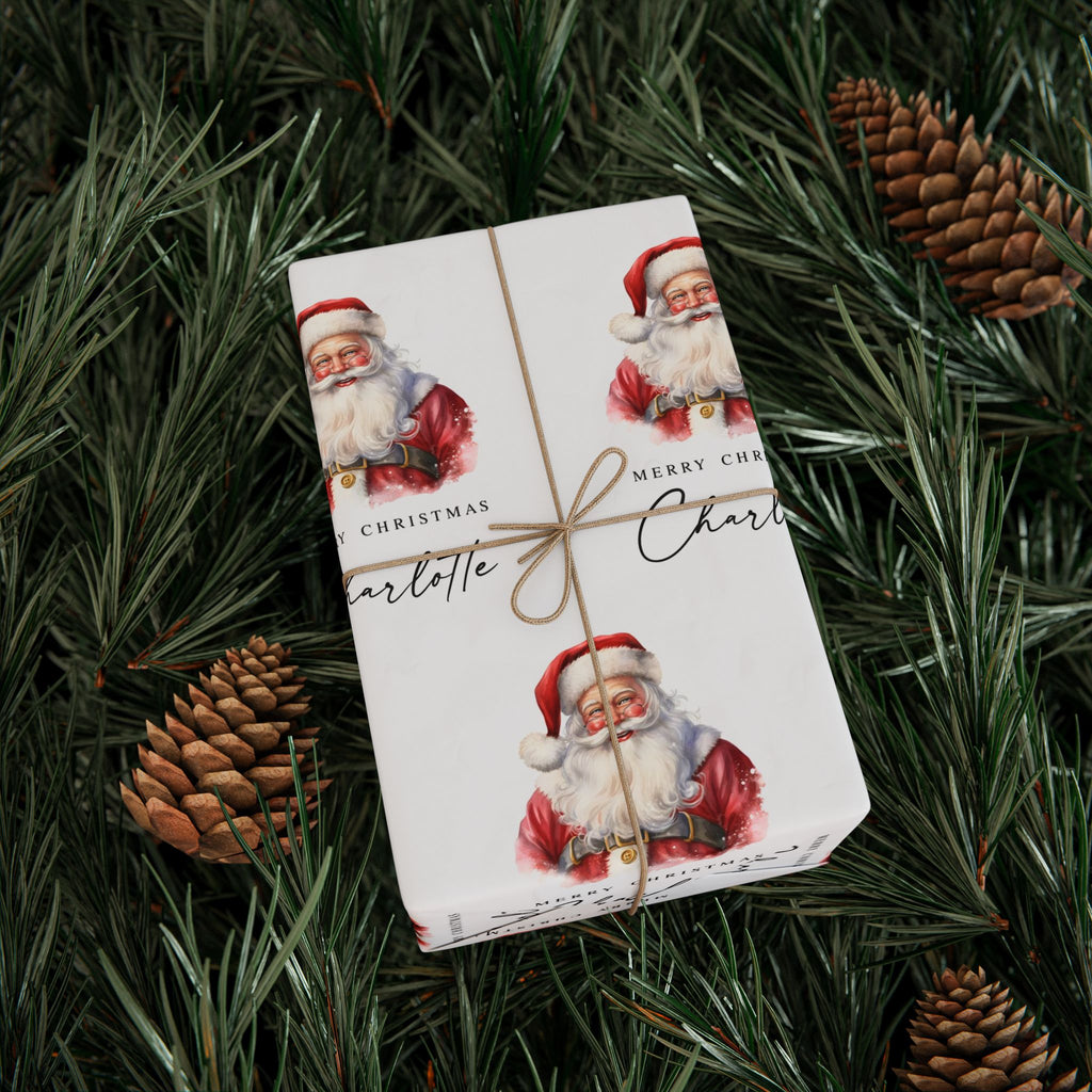 A personalised wrapped gift box with a classic Santa Claus pattern, tied with twine, placed on a bed of pine branches and pinecones.