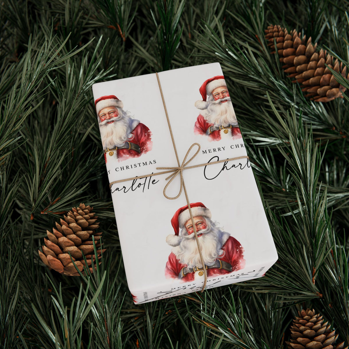 A personalised wrapped gift box with a classic Santa Claus pattern, tied with twine, placed on a bed of pine branches and pinecones.