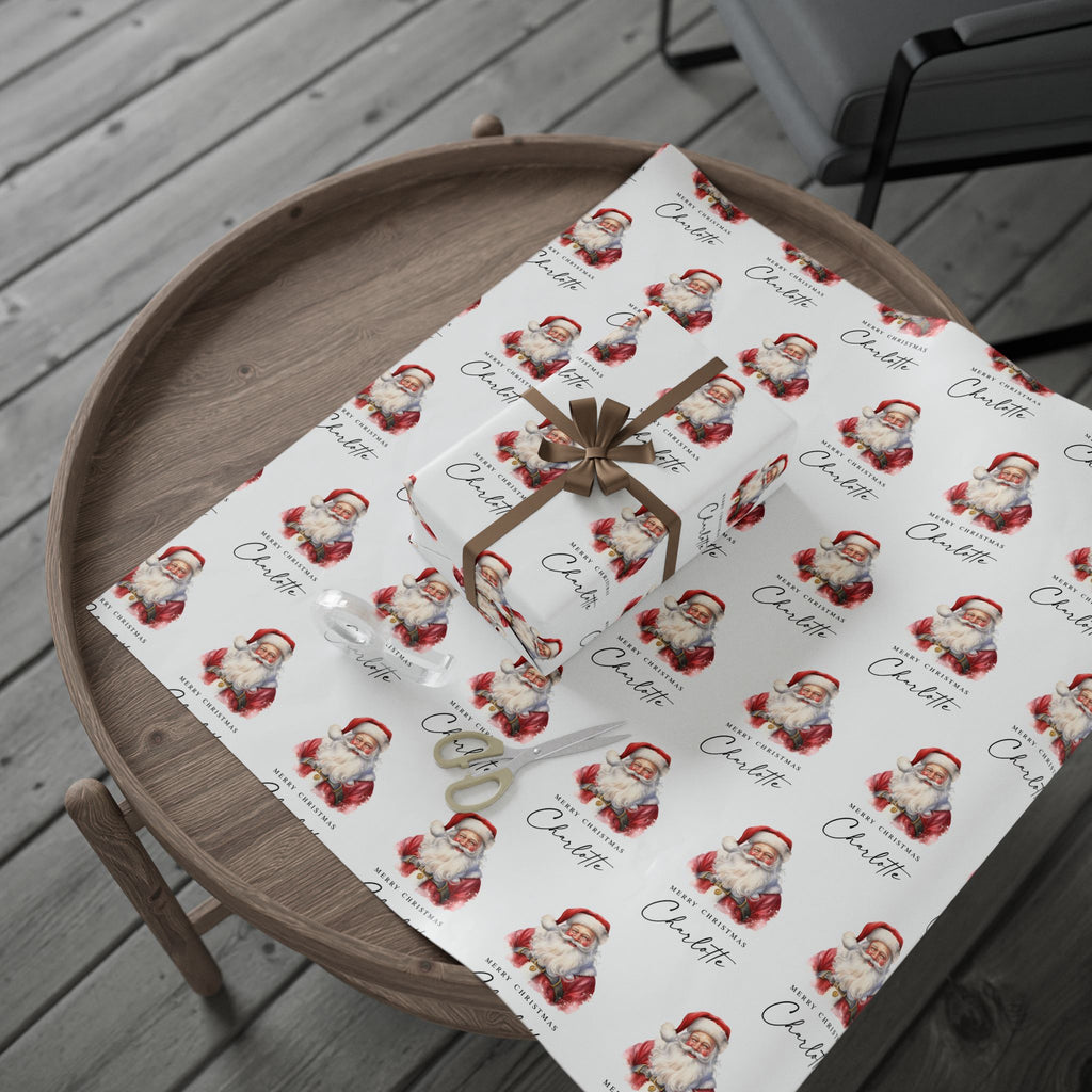 Personalised Christmas wrapping paper featuring classic watercolour Santa Claus design, displayed unrolled with a wrapped gift on a wooden tray