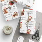 Three gift wrapped boxes arranged on a light grey surface with wrapping paper printed with Christmas teddy bears, the text 'Merry Christmas Theodore.' A ball of twine, scissors, and small round tags are placed nearby as styling props.
