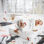White Christmas themed wrapping paper with teddy bear illustrations and black script text, shown wrapped around gift boxes on a table near a window. Scissors and ribbon are visible in the scene.